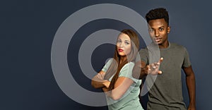 Man and woman studio portrait office workers team crossed arms pointing at camera on gray background