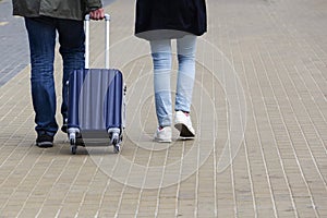 A man and a woman with a suitcase are on the sidewalk. Tourism and travel