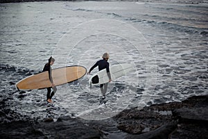 Man and woman with surfboards going to water