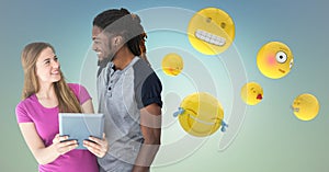 Man and woman with tablet and emojis against blue green background