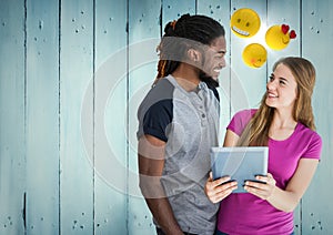 Man and woman with tablet and emojis against blue wood panel