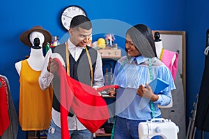 Man and woman tailors holding touchpad and t shirt at sewing studio