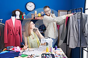 Man and woman tailors smiling confident working at clothing factory