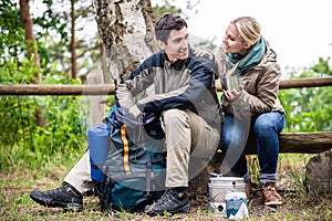 Man and woman take break from hiking and cook