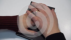 A man and a woman take an oath on the Bible. The hands of the newlyweds with rings are placed on the bible close-up.