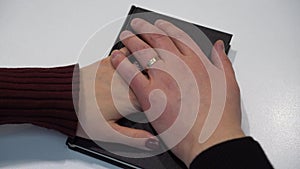 A man and a woman take an oath on the Bible. The hands of the newlyweds with rings are placed on the bible close-up.