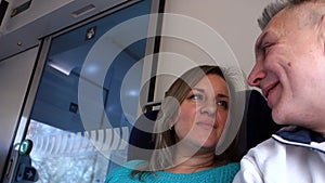 Man and woman talk in moving train. Couple of middle aged people speaks in public transport railway or metro sitting and smiling.