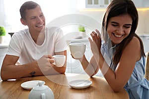 Man and woman talking while drinking tea at table in kitchen