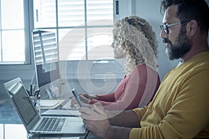 Man and woman team work together in couple at home with technology and online connection laptop computer and phone - smart working