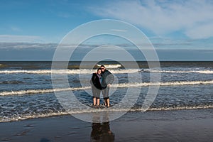 Man and woman in their thirties standing with their feet in the sea