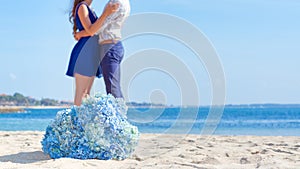 Man and woman together at the beach with blue flowers in-focus i