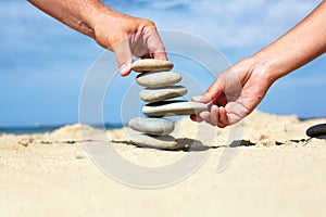 Man and woman together to build a tower made of stones.