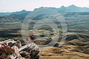 A man and a woman in tourist equipment are standing on a rock and admiring the panoramic view.