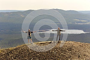 Man and woman tourists stand on the top of Poklonnaya Gora against the background of the Ural Mountains