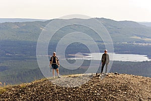 Man and woman tourists stand on the top of Poklonnaya Gora against the background of the Ural Mountains, Ilmenskaya ridge