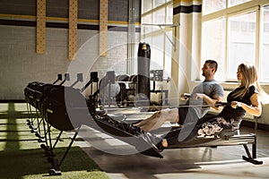 Man and woman training on rowing machines in gym together