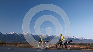 The man and woman travel on mixed terrain cycle touring with bikepacking. The couple journey with bicycle bags. Mountain