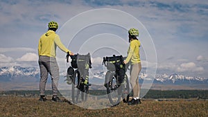 The man and woman travel on mixed terrain cycle touring with bikepacking. The love couple journey with tent in with