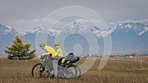 The man and woman travel on mixed terrain cycle touring with bikepacking. The love couple journey with tent in with