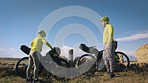 The man and woman travel on mixed terrain cycle touring with bikepacking. The two people journey with bicycle bags