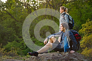 Man and woman traveler outdoors. Hikers couple takes a rest during hiking. Travel, vacation, holidays and adventure concept.