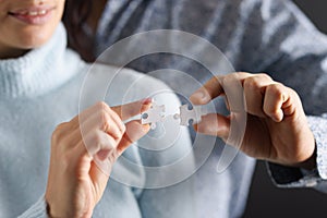 Man and woman are trying to connect white puzzles together