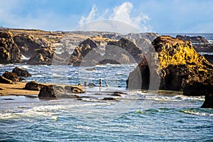 Man and woman with two dogs walking on Northern California beach with huge outcroppings - view from above