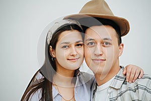 A man and a woman under the same hat, hugging and posing