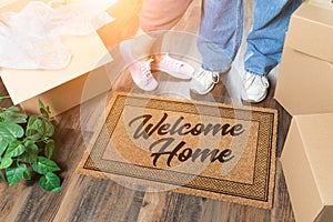 Man and Woman Unpacking Near Welcome Home Welcome Mat, Moving Boxes and Plant photo