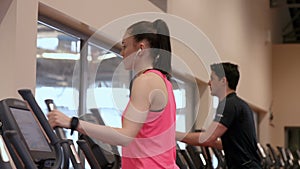 Man and woman using the cross trainers in gym