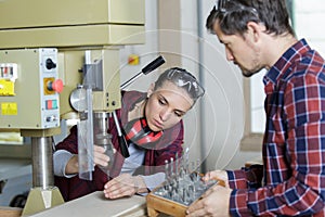 man and woman using drill machine in workshop
