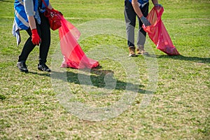 Man and woman volunteer wearing picking up trash and plastic waste in public park. Young people wearing gloves and putting litter