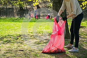 Man and woman volunteer wearing picking up trash and plastic waste in public park. Young people wearing gloves and putting litter