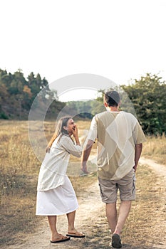 A man and a woman are walking in a field, a happy couple.
