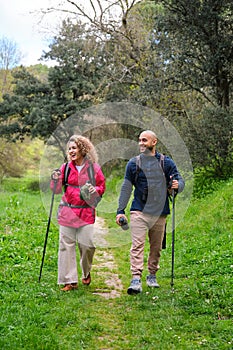 A man and a woman are walking in a forest. Trekking and hiking.