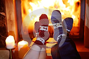 Man and woman in warm socks near fireplace