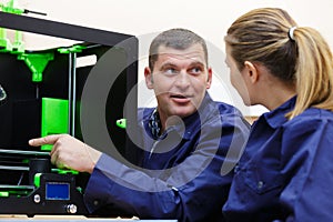 man and woman wearing overalls using 3d printer photo