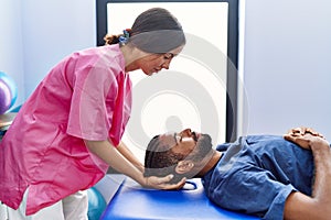 Man and woman wearing physiotherapist uniform having reiki session at physiotherpy clinic