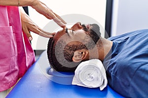 Man and woman wearing physiotherapist uniform having reiki session at physiotherpy clinic