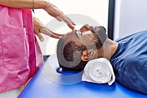 Man and woman wearing physiotherapist uniform having reiki session at physiotherpy clinic