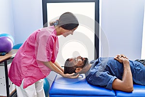 Man and woman wearing physiotherapist uniform having reiki session at physiotherpy clinic