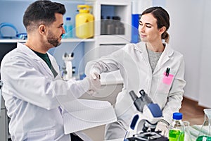 Man and woman wearing scientist uniform shake hands at laboratory