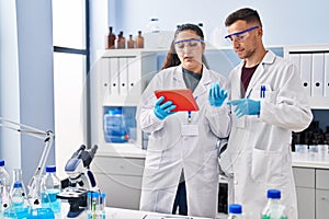 Man and woman wearing scientist uniform using touchpad at laboratory