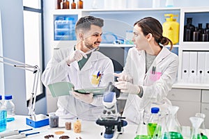 Man and woman wearing scientist uniform writing on notebook at laboratory