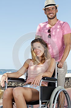 man with woman in wheelchair on beach