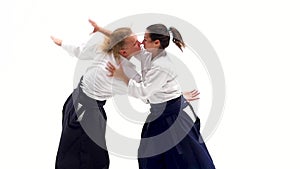 Man and woman in white keikogi showing aikido techniques, isolated on white. Close up.