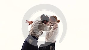 Man and woman in white keikogi showing aikido techniques, isolated on white. Close up. Slow motion.
