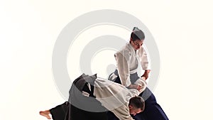 Man and woman in white keikogi showing aikido techniques, isolated on white. Close up. Slow motion.