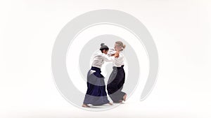 Man and woman in white keikogi showing aikido techniques, isolated on white. Slow motion.