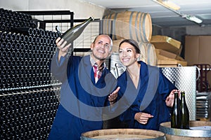 Man and woman winemakers in wine cellar